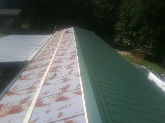 Old rusted panels beside newly installed green metal roofing — Wind Damage Roof Repair by Roofing Brothers in Plymouth